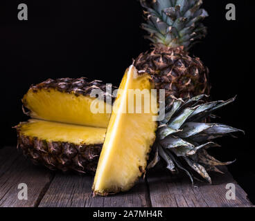 Ananas a fette sulla vecchia scrivania rustico sfondo nero. Foto Stock