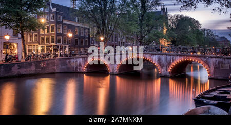 Vista di un ponte su un canale ad Amsterdam durante il tramonto Foto Stock