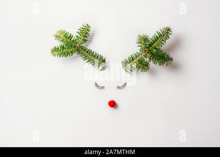 Natale renne concetto fatta di evergreen fir, ninnolo decorazione, linguette e palchi pastello su sfondo chiaro. Il minimo vacanze invernali idea. L piatto Foto Stock