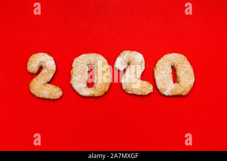 Nuovo anno. Le figure 2020 fatta di biscotti di Natale su uno sfondo di colore rosso. Foto Stock