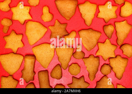 Festosa fatti a mano biscotti a forma di stelle, alberi di Natale, cuori, campane per Natale e Capodanno Vacanze su uno sfondo di colore rosso. Vista dall'alto. Foto Stock