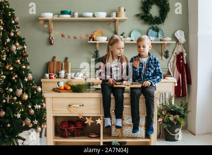 Ritratto di un piccolo fratello e sorella in attesa di Santa in cucina Foto Stock