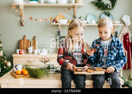 Ritratto di un piccolo fratello e sorella in attesa di Santa in cucina Foto Stock