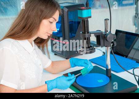 Lavoratore di sesso femminile nel controllo di resina LCD / DLP / SLA stampante 3D nel laboratorio di tecnologia Foto Stock