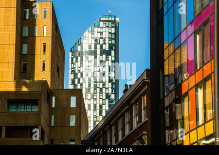 Una slanciata torre rivestita di vetro – forse la torre Beetham di 90 metri (Torre Ovest), costruita nel 2004 dall'architetto Ian Simpson in Old Hall Street – si erge tra edifici più antichi in mattoni e arenaria e una facciata colorata in vetrata nel centro di Liverpool, Inghilterra. Foto Stock