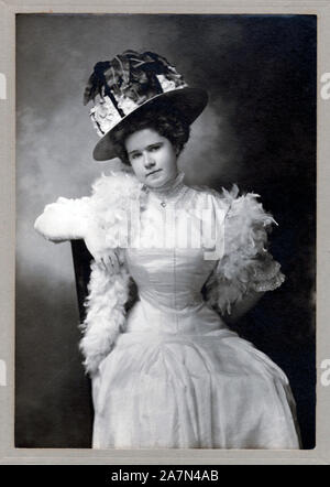 Cabinet Vintage card che mostra una giovane donna che indossa un cappello di fantasia, abito e feathered scialle, circa 1915, STATI UNITI D'AMERICA. Foto Stock