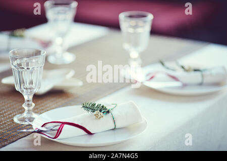 Close up di elegante messa in tavola per la cena di Natale: tovaglioli bianco legato con abete decorazioni in viola interno, spazio di copia Foto Stock