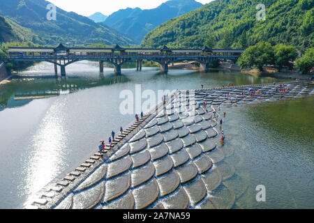 I visitatori un tuffo per rinfrescarsi in acqua in una posizione nota per il pesce in scala barriere sagomati che formano piccole cascate nel quartiere Fuyang, Hangzhou ci Foto Stock