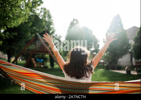 Tween girl prendendo una pausa mentre oscillanti in amaca in cortile Foto Stock
