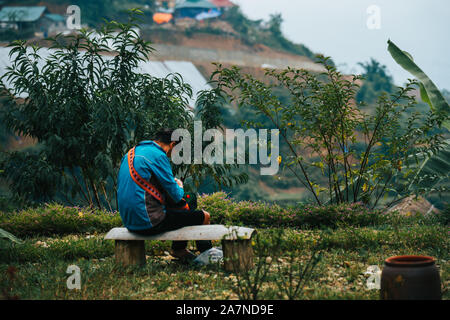 Un locale donna vietnamita produce abiti circondato da terrazze di riso nella piccola città di montagna Sapa nelle montagne a nord dell Indocina Foto Stock