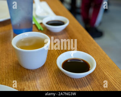 Bicchiere di tè e una piccola ciotola di salsa di soia in un ristorante tabella Foto Stock