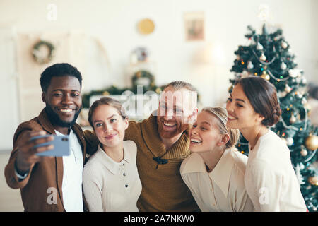 Gruppo di elegante adulto persone sorridenti in telecamera tenendo selfie foto durante la festa di Natale, spazio di copia Foto Stock