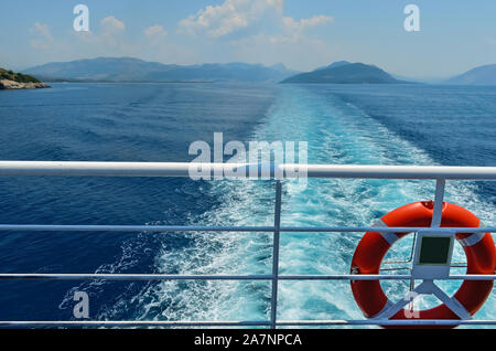 Vista posteriore del mare Ionio contro sky e isole dal balcone di una nave traghetto .Red benedizione sul ponte di una nave traghetto. La vacanza estiva in greco Foto Stock