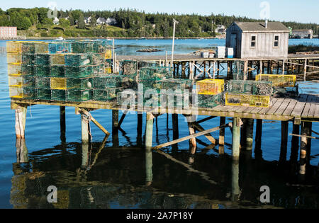 Un molo su porto basso nel Maine ha molti giallo e green lobster trappole Impilati e pronti per essere immessi in acqua. Foto Stock