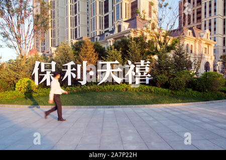 --FILE--un residente locale passeggiate passato un appartamento progetto di poli sviluppi e aziende Group Co., conosciuto anche come Poly Real Estate, nella città di Dalian, Foto Stock