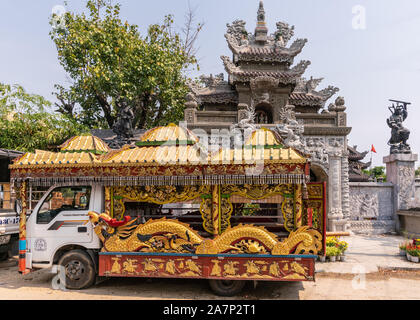 Da Nang, Vietnam - Marzo 10, 2019: Van ricostruita come oro-rosso funebre con elaborate decorazioni di draghi e simboli mitologici di fronte a lungo un C Foto Stock