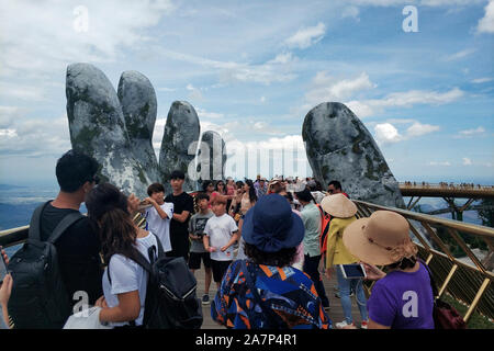 Turisti visitano il Golden Bridge detenute fino a mano statue circondato da nebbia e nuvole al Bana Hills di Da Nang, Vietnam, 19 agosto 2019. Bana H Foto Stock