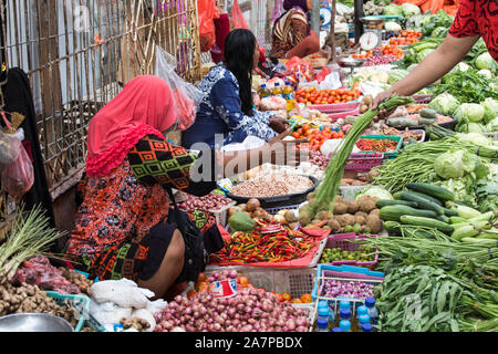 Labuanbajo, Indonesia - Agosto 17, 2015: gruppo non identificato di donne che indossano hijab e guarnizioni tradizionali vendono frutta tropicale in strada Foto Stock