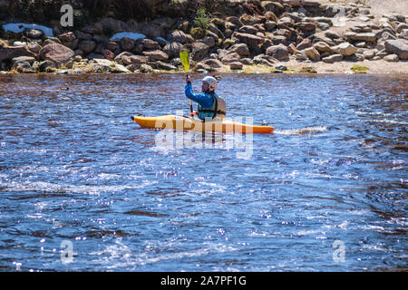 L'uomo sul kayak. Un uomo sulla banca del fiume sono in appoggio versando acqua da imbarcazioni che trasportano il kayak sul fiume.una vista dello sport è il kayak. Foto Stock