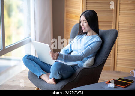 Libero professionista lavorando sul computer portatile mentre è seduto in poltrona Foto Stock