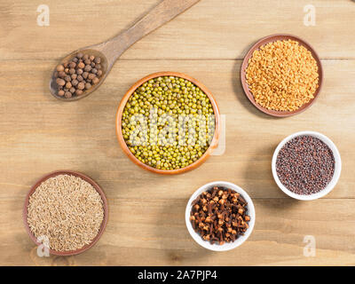 Pepe della Giamaica, Mung bean, semi di senape, fieno greco, cumino, i chiodi di garofano in legno marrone dello sfondo. La cucina indiana, Ayurveda, naturopatia, moderno speziale conc Foto Stock