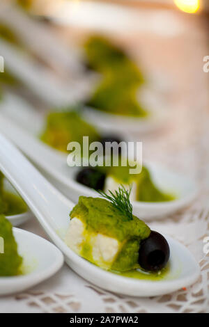 Gustosi e colorati antipasti verde essendo servito a cucchiaiate su di una piastra su un party Foto Stock