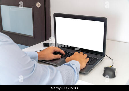 Persona che lavora su un computer portatile in un ufficio business ambiente. Oltre la spalla shot di man digitando su un computer con schermo vuoto. Foto Stock