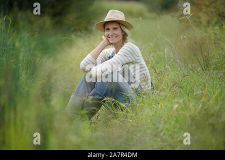 Sorridente agricoltore donna rilassante nel campo Foto Stock