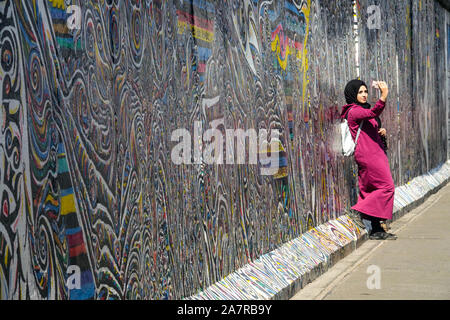 Berlino muro donna giovane donna araba prendere un selfie a. East Side Gallery Germania Foto Stock