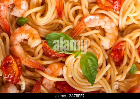 Pasta spaghetti con gamberi e pomodori secchi e basilico closeup. Pasto sano. Il cibo italiano. Foto Stock