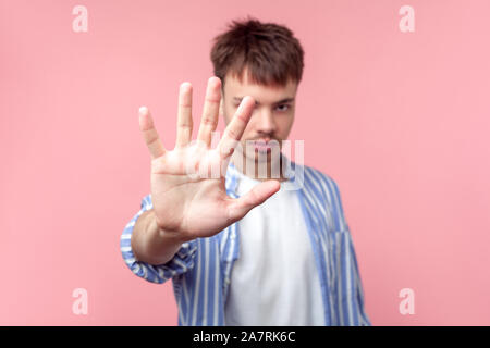 Stop! Ritratto di giovane serio i capelli castani uomo con piccola barba e baffi in casual striped shirt gesticolando stop, mostrando un cartello di segnalazione a telecamera. Foto Stock