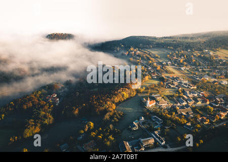 Piccolo centro abitato durante l'alba con nebbia. circondato da colline in Austria inferiore. Antenna fuco foto Foto Stock