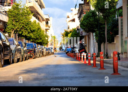 La zona pedonale di una parte della strada è diviso da red road colonne su una strada di città sotto la luce diretta del sole. Foto Stock