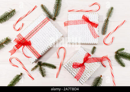 Sfondo di natale. Doni, Abete rami, decorazioni rosso su bianco sullo sfondo di legno. Natale, inverno, anno nuovo concetto. Piatto, laici vista superiore Foto Stock