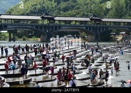 I visitatori un tuffo per rinfrescarsi in acqua in una posizione nota per il pesce in scala barriere sagomati che formano piccole cascate nel quartiere Fuyang, Hangzhou ci Foto Stock