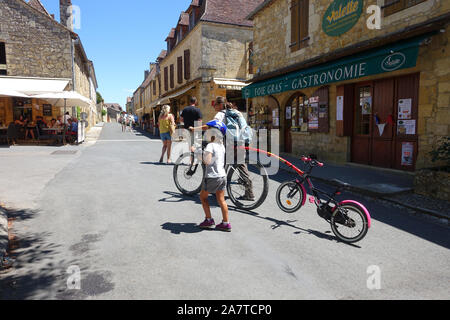 Domme, Francia 15 luglio 2019: turisti tra cui una madre e figlia con le loro biciclette nel centro di Domme nella regione della Dordogne della Francia Foto Stock