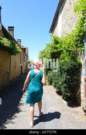 Domme, Francia 15 luglio 2019: un turista femminile esplorando il retro streest di La bastide città di Domme francesi nella regione Dordogna. Foto Stock