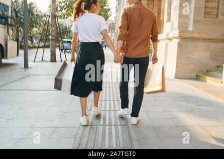 Abbassare la sezione corpo di un giovane turista giovane a piedi da store windows e tenendo la carta shopping bags in una città di destinazione. Foto Stock