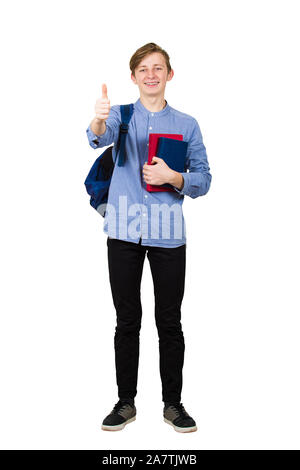 A piena lunghezza Ritratto di giovane studente ragazzo tenendo due libri al petto e portando il suo zaino sulla strada per la scuola. Adolescente che mostra il pollice fino positiv Foto Stock