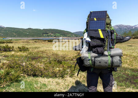 Caricabatterie solare su uno zaino nel tipico paesaggio scandinavo Foto Stock