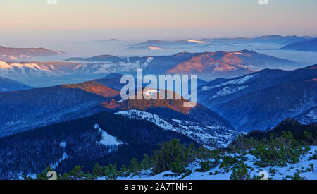 Paesaggio al tramonto sulle misty valley nei Carpazi romeni, Ceahlau mountain scena invernale Foto Stock