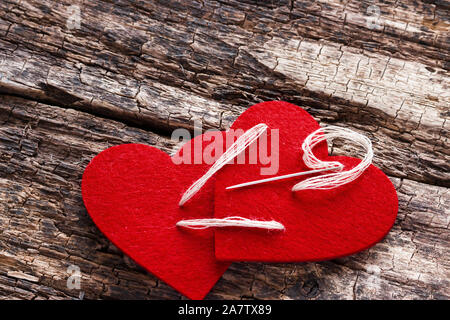 Cuore rosso cucito insieme su un sfondo di legno Foto Stock