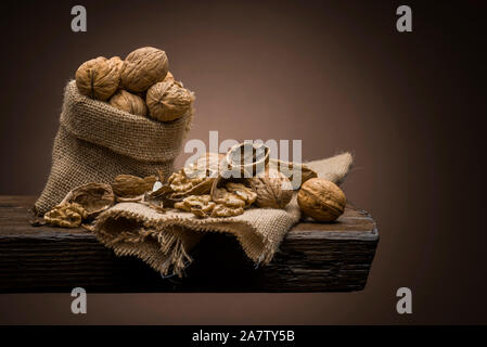 Le noci nel sacco di iuta sul tavolo di legno con sfondo scuro Foto Stock