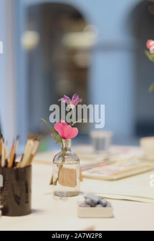 Bottiglia in vetro con rosa e viola viola tulip sul tavolo in art studio Foto Stock