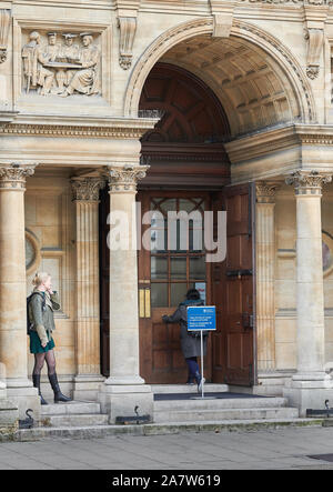 Una studentessa ha una conversazione telefonica in piedi fuori l'ingresso agli esami di scuole, università di Oxford, Inghilterra. Foto Stock