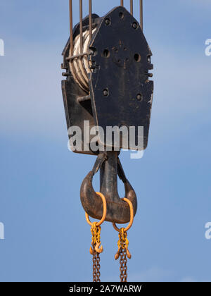 Il gancio della gru con strisce rosse e bianche pensili, cielo blu in background. Foto Stock