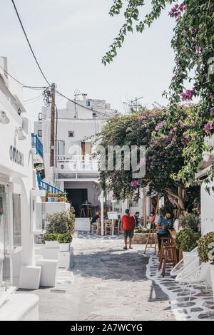 La città di Mykonos, Grecia - 23 Settembre 2019: l'uomo in t-shirt rossa passato a piedi i negozi e i ristoranti su una strada stretta in Hora (noto anche come traino di Mykonos Foto Stock