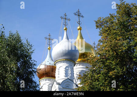 Chiesa Russa con cupole d oro guarda attraverso i rami di alberi oltre il cielo blu chiaro Foto Stock