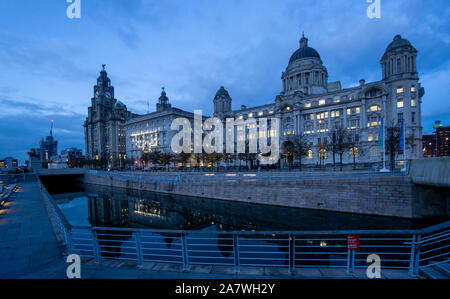 I tre edifici Graces, il Royal Liver Building, il Cunard Building e il Port of Liverpool Building, visti di notte al Pier Head di Liverpool Foto Stock