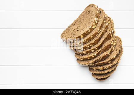 Insieme a fette di pane di grano con fiocchi di avena. Pane integrale sul tavolo bianco. Vista dall'alto. Foto Stock